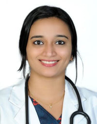 A smiling female doctor wearing a white coat and stethoscope, posed against a plain background.