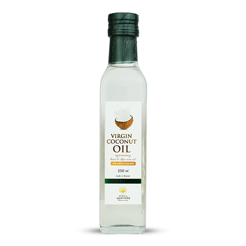 Front view of a clear glass bottle of Kerala Ayurveda Virgin Coconut Oil, with a green cap and a white label featuring a coconut splash graphic and the product name. It indicates "250 ml". – Kerala Ayurveda India