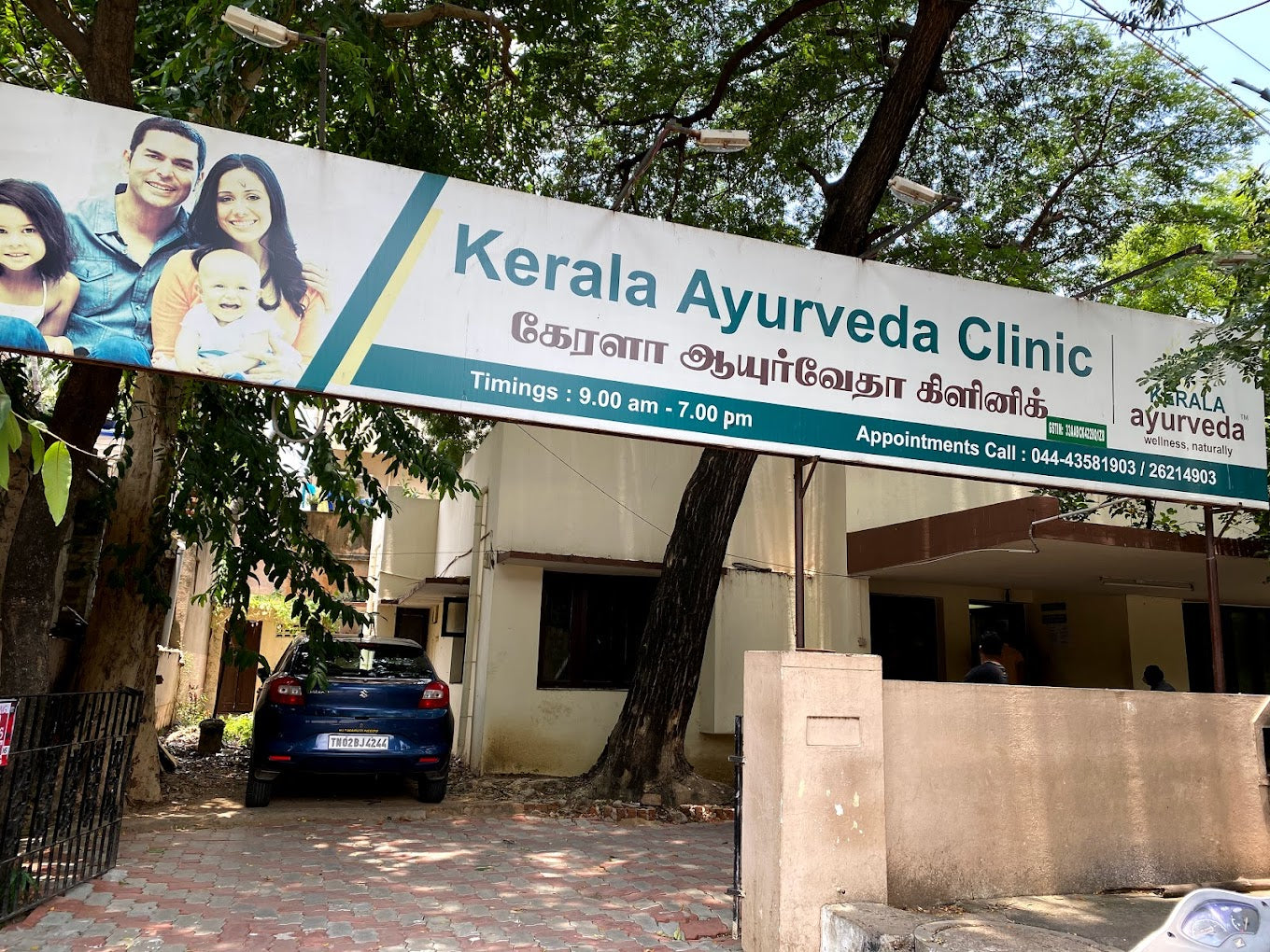 Sign for Kerala Ayurveda Clinic with family images, timings 9:00 AM - 7:00 PM, and contact details displayed.